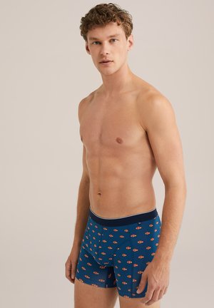 Boxer shorts in dark blue fabric featuring a repeating fish pattern in orange and white; elastic waistband with a navy accent.