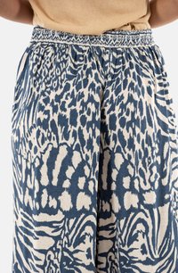 Pantaloni fluidi con vita elasticizzata, caratterizzati da un audace design animalier blu e crema e tessuto testurizzato.