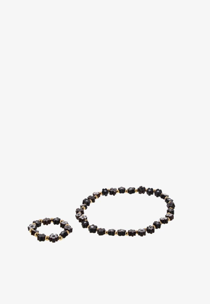 Collier de perles en forme de fleur noire et bracelet assorti séparés sur fond blanc avec de petites perles intercalaires dorées.