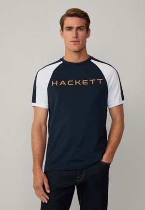 Camiseta de manga corta azul marino con mangas raglán blancas y logo dorado "HACKETT". Fabricada en mezcla de algodón, con textura suave y corte clásico.
