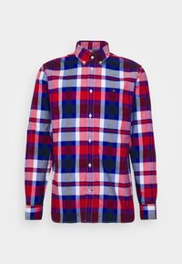 Camisa de cuadros en rojo, azul y gris, con botones, mangas largas y cuello. Presenta un pequeño logotipo en el pecho y botones blancos.