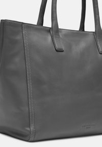 Szara skórzana torba tote z podwójnymi uchwytami, gładką teksturą, bocznymi szwami i wytłoczonym logo marki. Prosty kształt o minimalistycznym designie.