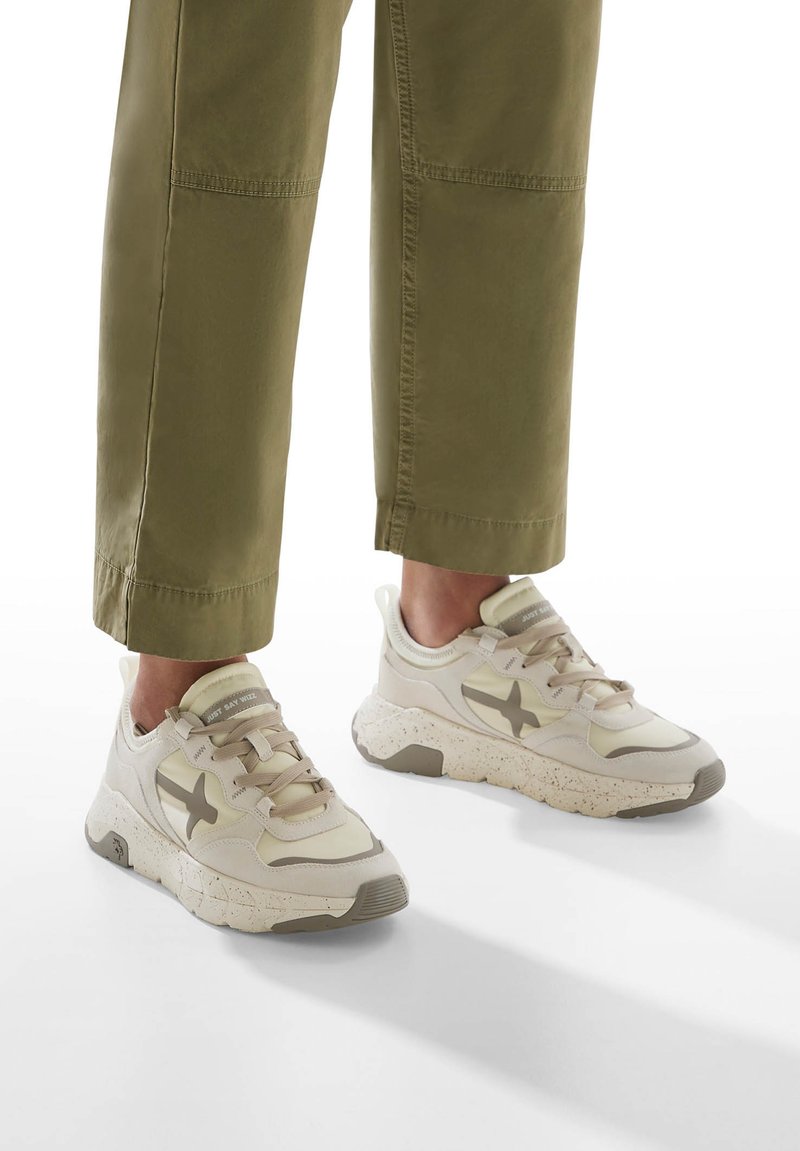 Sneakers beige chiaro con tomaia strutturata, caratterizzati da una stella di un beige più scuro e una suola maculata. I lacci sono piatti e coordinati con il colore.