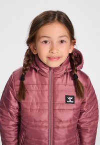 Veste isolée bordeaux avec capuche, fermeture éclair à l'avant et patch logo noir. Texture matelassée avec des coutures visibles et des accents à cordon.