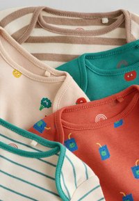 Neljä lasten t-paitaa pehmeää puuvillaa: beige keltaisella hymyilijällä, vihreä sateenkaarella, raidallinen kerma tealilla ja oranssi mehu-uutepakkauksilla.