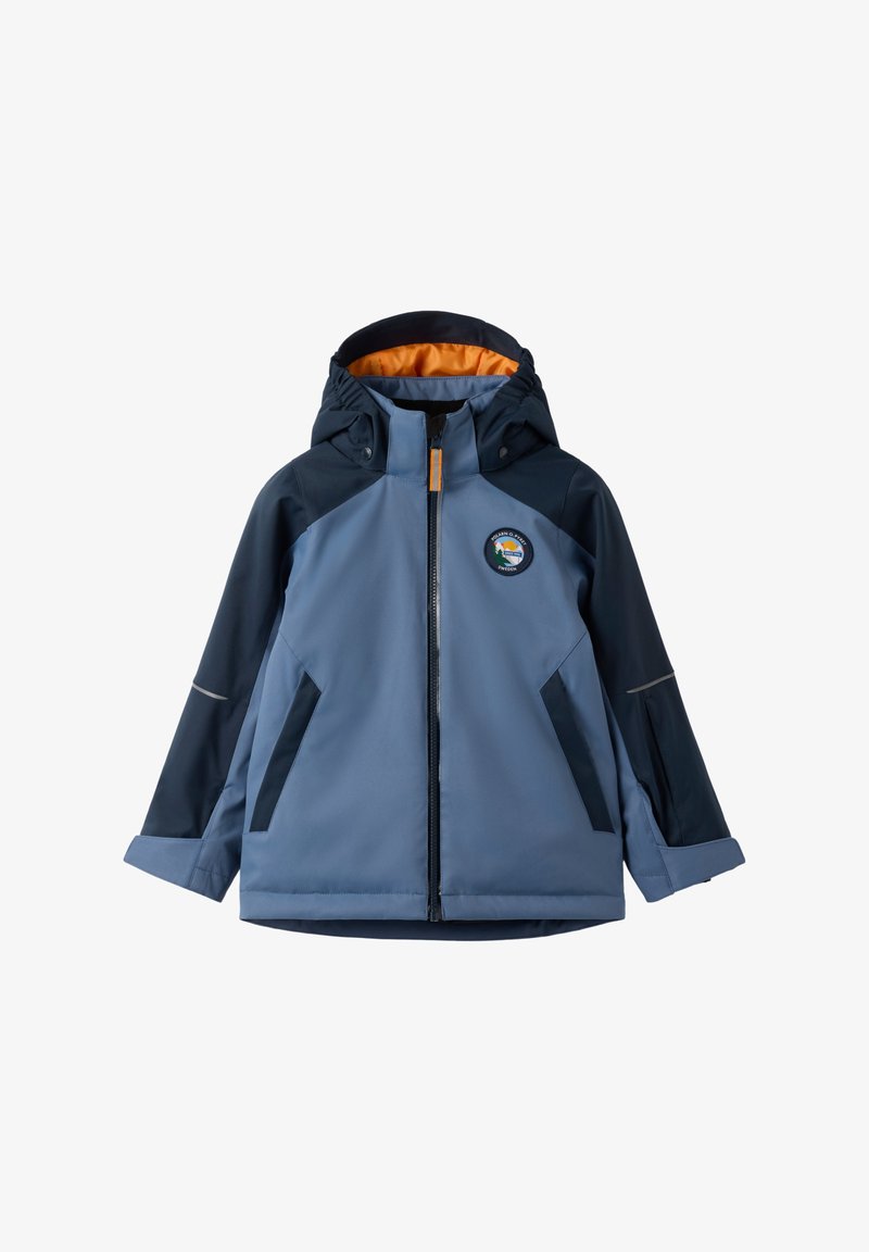 Sininen vedenpitävä takki hupulla, oranssi vuori, etuvetoketju, heijastavat yksityiskohdat ja pyöreä logo vasemmassa rinnassa.