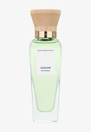 Grande bouteille de parfum en verre transparent avec un liquide vert clair, bouchon en bois et étiquette portant la mention « Adolfo Dominguez Azahar Aguafresca ».