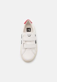 Witte sneaker met rode en marineblauwe accenten, gemaakt van glad leer, met twee klittenbandsluitingen, ronde neus en een gestructureerde rubberen zool.