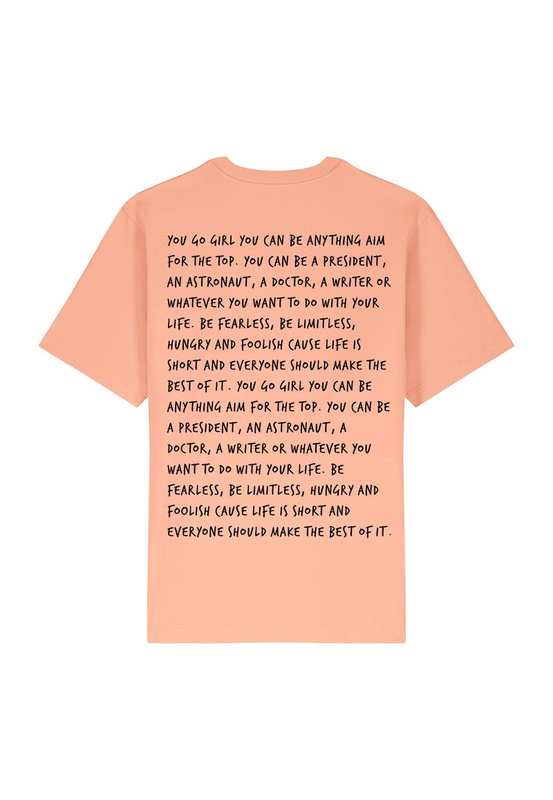 T-shirt à manches courtes couleur pêche avec un texte noir au dos comportant des phrases motivantes sur l'ambition et la confiance en soi.