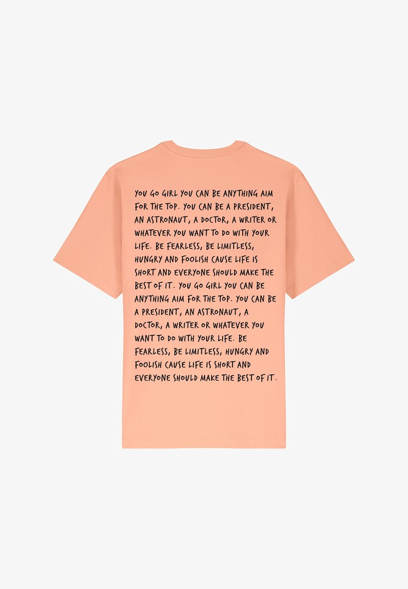 T-shirt à manches courtes couleur pêche avec un texte noir au dos comportant des phrases motivantes sur l'ambition et la confiance en soi.
