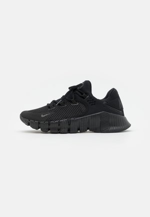 Sort atletisk sneaker med mesh-overdel, tyk segmenteret sål, snørebånd og subtil Nike-logo på siden og hælen.