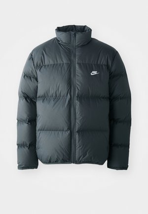 Crna puffer jakna s quiltanim dijelovima, visokim ovratnikom i prednjim patentnim zatvaračem. Sadrži mali bijeli Nike logo na prsima.