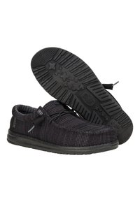 Schwarze gewebte Stoffschuhe mit strukturierter Oberfläche, ausgestattet mit einer flexiblen Sohle und elastischen Schnürsenkeln, präsentiert mit sichtbarer Sohle.