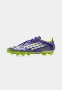 Purple soccer cleat with green accents, featuring a sleek design, textured upper, and durable studs for traction on grass surfaces.
