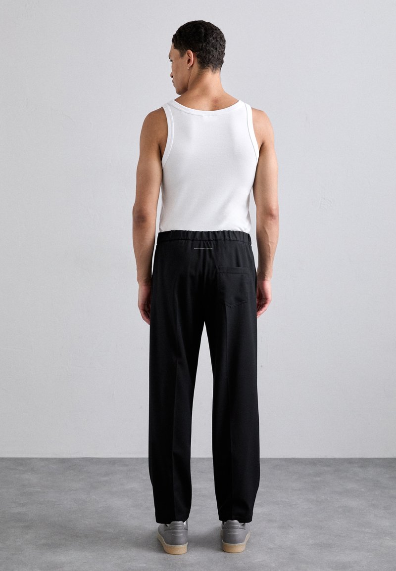 Sorte bukser med en afslappet pasform og elastisk talje, parret med en enkel hvid tanktop. Stoffet ser glat ud uden mønstre.