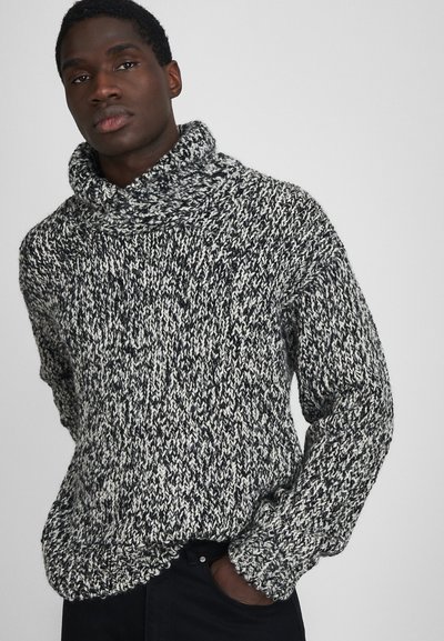 Schwarzer und weißer, grob gestrickter Pullover mit hohem, umgeschlagenem Kragen. Verfügt über lange Ärmel und ein strukturiertes Muster im gesamten Design.