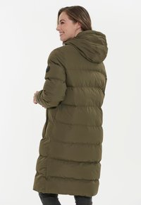 Abrigo acolchado color verde oliva con capucha, que cuenta con un diseño acolchado, dos bolsillos laterales y un parche con el logo en la manga izquierda.