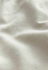 Svijetlosmeđi materijal s glatkom teksturom, s blagim nabora i jednostavnim tkanjem. Materijal izgleda mekan i lagan.