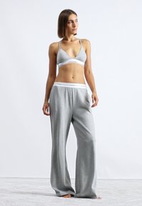 Grå bomulls-bralette med V-hals og logo-acsentert bånd, kombinert med løstsittende grå bukser med elastisk midje og myk tekstur.