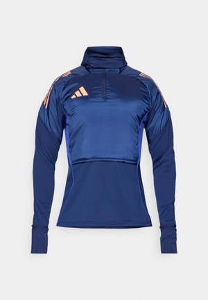 Námořnický modrý sportovní pulovr s vysokým límcem, čtvrtinovým zipem a dlouhými rukávy. Má lehký materiál a růžové akcentové pruhy na ramenou.
