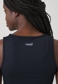 Čierny športový tielko s okrúhlym výstrihom a malým bielym logom "casall" na chrbte. Hladká textúra a priliehavý strih.