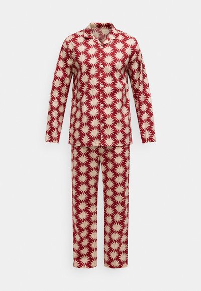 Set de pijamale roșu și crem, cu model, format dintr-o cămașă cu mâneci lungi și guler, și pantaloni asortați, ambele decorate cu motive stelate.