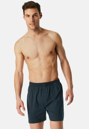 Boxers en coton bleu foncé pour hommes avec une taille élastique, une fermeture à bouton à l'avant et des coutures minimales pour le confort.