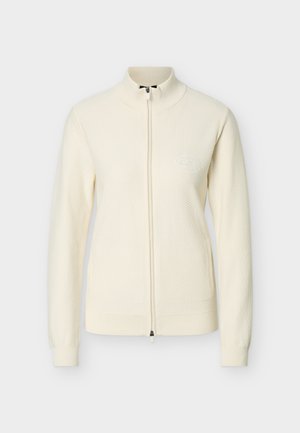 Krém színű, teljes cipzáras kötött pulóver magas gallérral és finom texturált mintával, a mellrészen egy kis dombornyomott logóval.