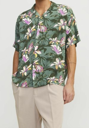 Camisa tropical de manga corta verde con patrones florales en rosa y blanco. Cuenta con un collar, botones y un ajuste relajado.