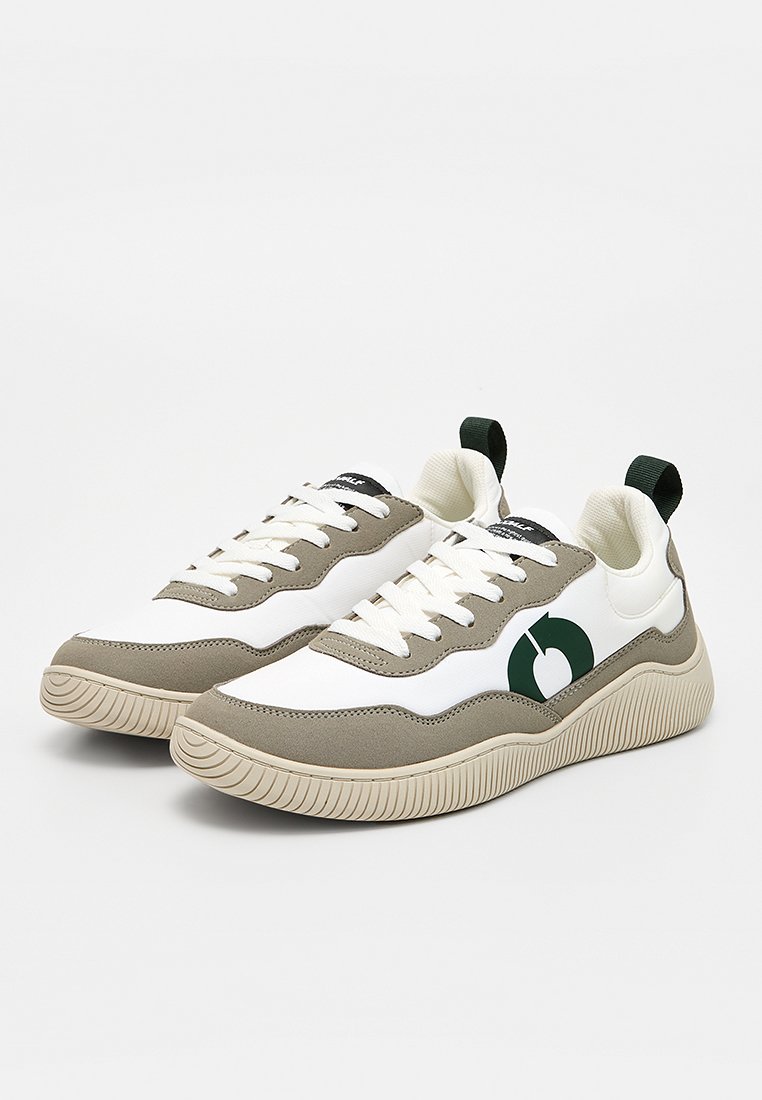 Zapatillas blancas y verdes oliva con una suela crema texturizada, que cuentan con un logotipo circular prominente, diseño con cordones y pestañas para tirar en el talón.