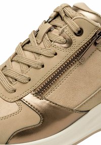 Sneaker beige con tomaia in pelle sintetica, dettagli metallici, cotone scamosciato testurizzato, lacci tondi e una chiusura lampo laterale per un accesso facile.