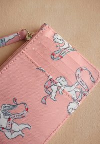 Portafoglio rosa realizzato in tessuto testurizzato, caratterizzato da cherubini illustrati e nastri; include scomparti per carte e una chiusura con zip.