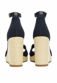 Navy canvas wedge sandals with a textured jute heel and adjustable ankle strap. Features a closed back and open sides for breathability.