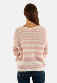 Pull surdimensionné rayé rose et blanc en tricot doux et duveteux, avec un large col et un ourlet côtelé. Porté avec un jean foncé, vu de dos.