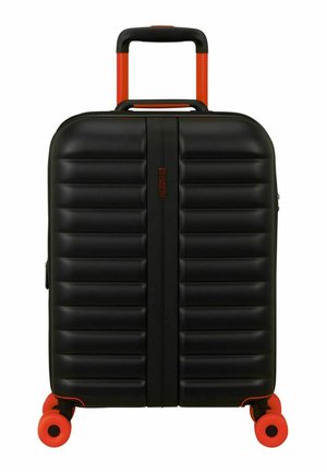 Valise rigide noire avec poignée rétractable orange et quatre roues orange, debout sur fond blanc.