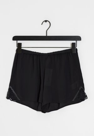 Schwarze locker sitzende Shorts mit elastischem Bund und Spitzenbesatz an den Seiten, an einem schwarzen Clipbügel vor weißem Hintergrund aufgehängt.
