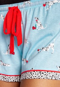 Blauwe shorts gemaakt van zachte stof met een patroon van zwarte en witte honden met harten. Rode koordjes en een zwart-witte stippenrand.