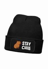 Black knitted beanie hat with a ribbed texture, featuring a rounded cuff and a patch that displays a capybara illustration and the text "STAY CHILL."