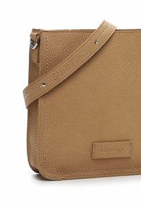 Borsa a tracolla in pelle tan con superficie texturizzata, hardware argentato e logo stampato. Presenta una tracolla removibile e bordi cuciti puliti.