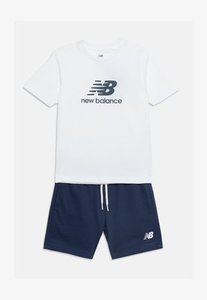 T-shirt blanc à manches courtes avec logo noir New Balance, associé à un short bleu marine à cordon de serrage doté d'un petit logo blanc sur la jambe.