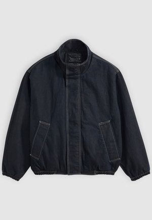 Veste bleu foncé avec un col montant, des poignets élastiques et deux poches avant. Détails de couture visibles et une coupe décontractée légèrement surdimensionnée.