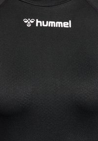 Czarna sportowa koszulka z krótkim rękawem, wykonana z teksturowanego materiału syntetycznego. Na obszarze klatki piersiowej znajduje się białe logo "hummel".