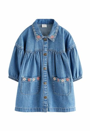 Robe en denim à manches bouffantes, boutons sur le devant et poches brodées de fleurs. Couleur bleu clair. Associée à des bottines de couleur pastel.