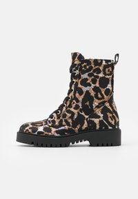 Botines de leopardo en negro y beige con punta redonda, suela gruesa negra, cordones en la parte delantera y una cinta para tirar en la parte posterior.