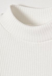 Witte geribde top met een hoge halslijn en gestructureerde stof. Het patroon bestaat uit verticale lijnen die een subtiele, gestructureerde uitstraling creëren.