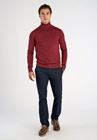 Maroon turtlenecktröja, figursydd design, lång ärm, i kombination med marinblå chinos och bruna segelskor med snörning och strukturerade sulor.