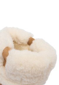Vzdušné, krémovo-biele vlnené papuče so jemnou textúrou a hnedými koženými detailmi pri otvore. Zaoblený tvar pre pohodlie.