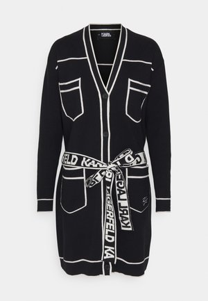 Zwarte cardigan met witte bies, voorzien van twee voorkruiden, knoopsluiting en een logo-belt met herhaaldelijke "KARL" tekst.