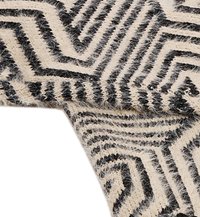 Črn in krem vzorčast tekstil z zigzag vzorci, z puhasto teksturo in kontrastnimi barvnimi odseki.