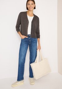 Cardigan grigio scuro con chiusura a bottoni, abbinato a jeans blu aderenti. Borsa a tracolla in crema dalla texture, sneakers chiare. Outfit semplice e casual.
